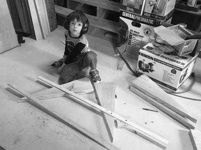 Lucas working on his woodworking project on the floor of the shop